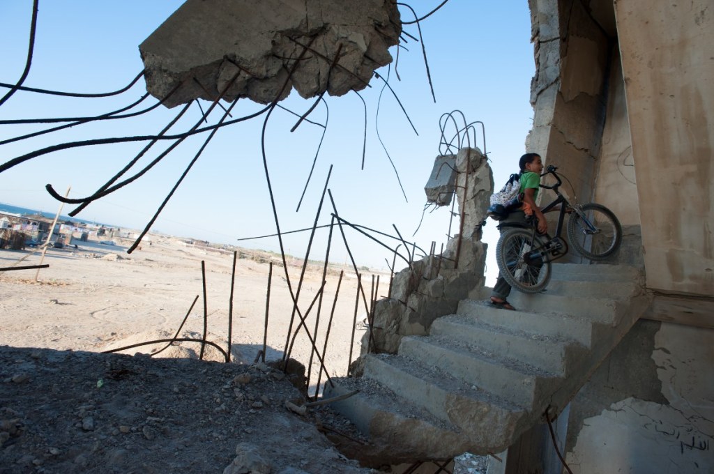 Child takes bicycle to destroyed home in Gaza, highlighting MAP International's emergency relief to Israel and Middle East